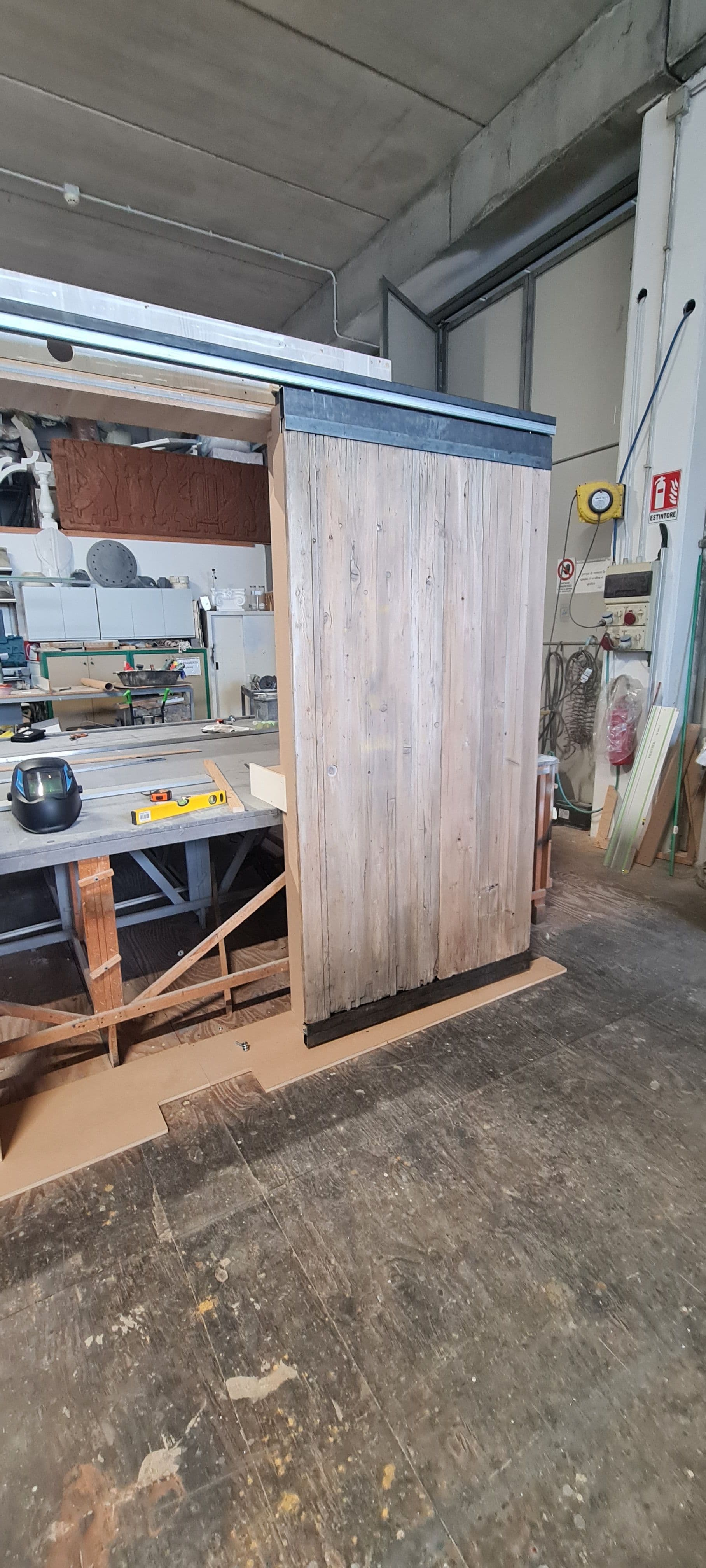 Prova di montaggio del pannello scorrevole in legno recuperato su binario industriale in laboratorio.
