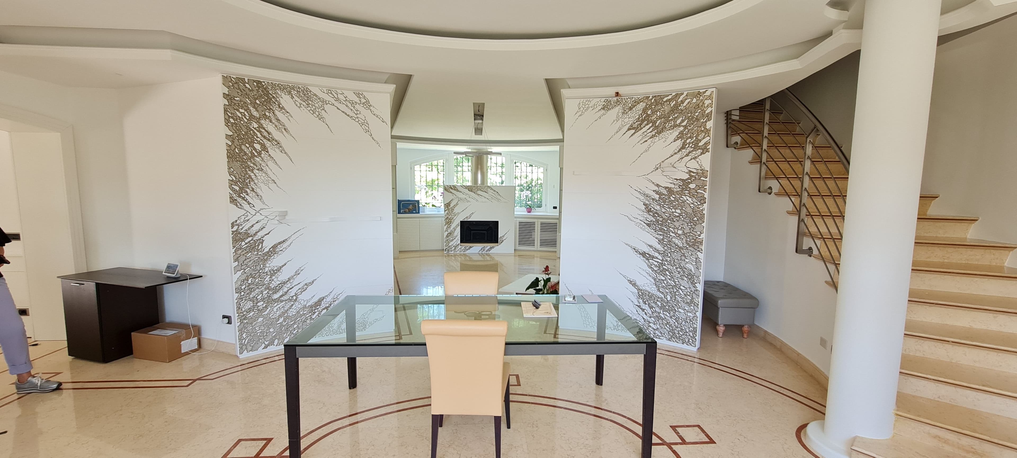 Ampio salone moderno con due grandi pannelli curvi decorati posizionati ai lati della zona pranzo.